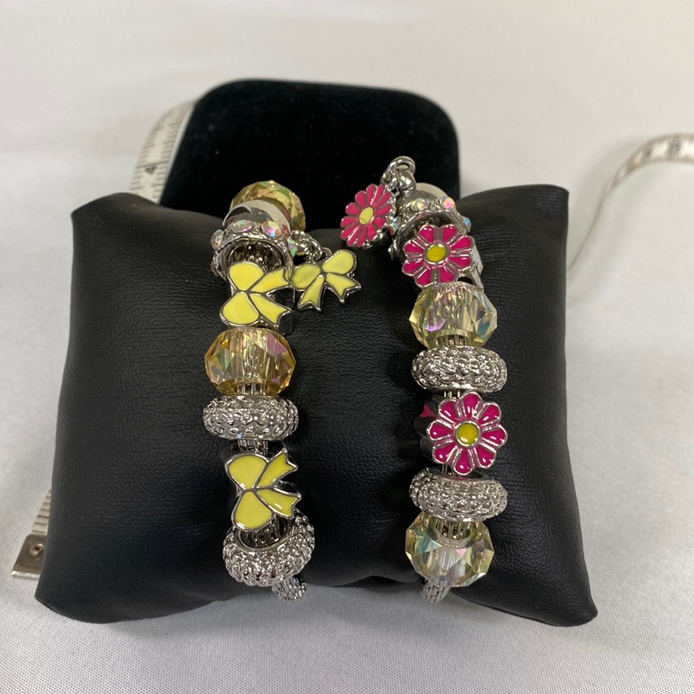 Two stretch charm style bracelets with bows and flowers